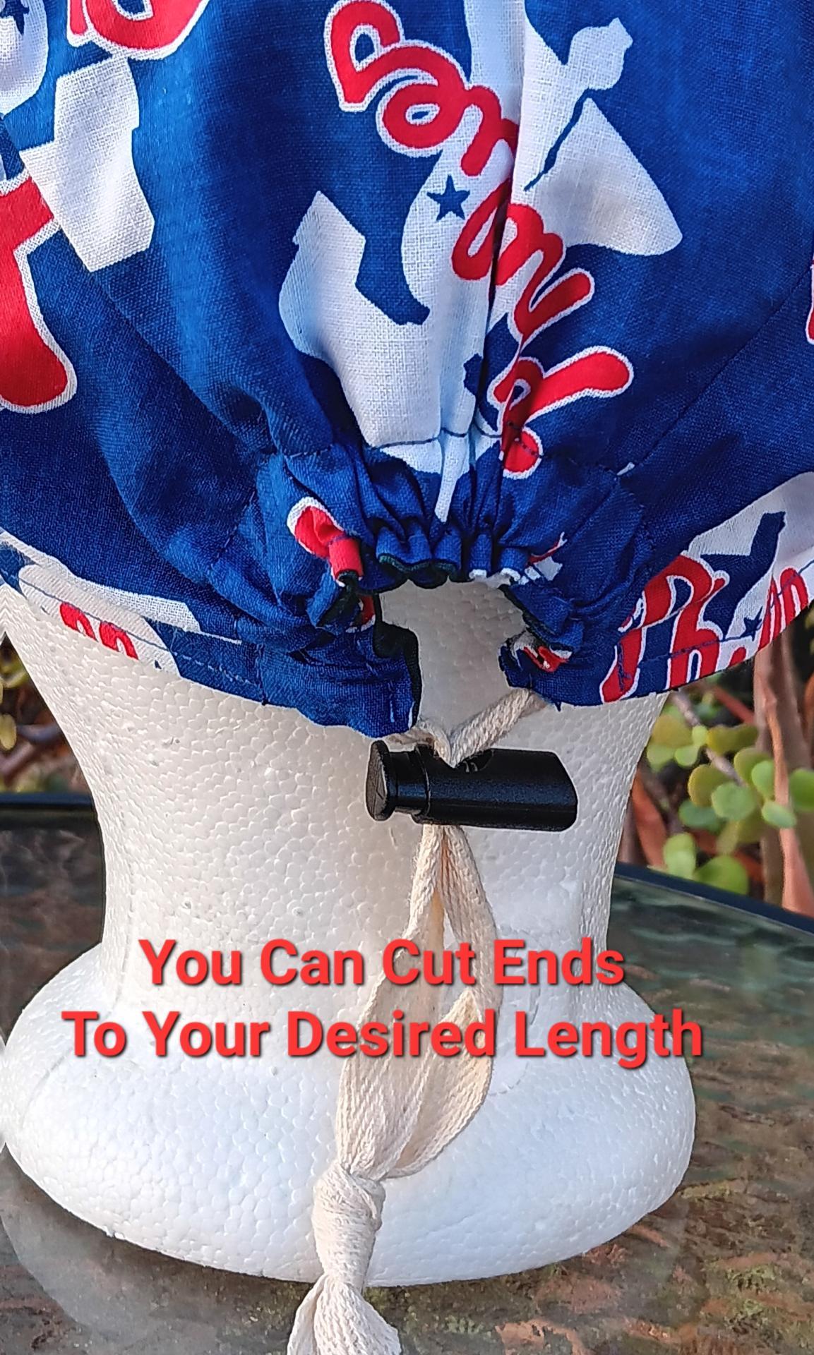 Back view of the Philadelphia Phillies and Eagles reversible scrub cap, showing the adjustable toggle closure, with text saying that the twill tape can be cut to desired length. Handmade from licensed fabrics.