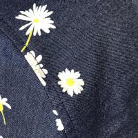 Close up showing small white daisies on denim