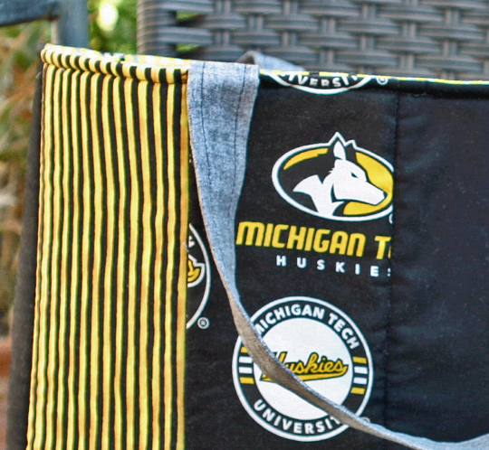 Close up of exterior showing grey strap attached to top of bag