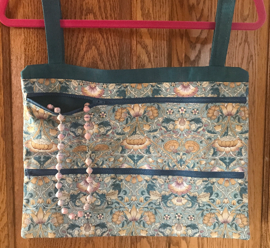 Two zipper pockets with necklace shown for scale (not included)