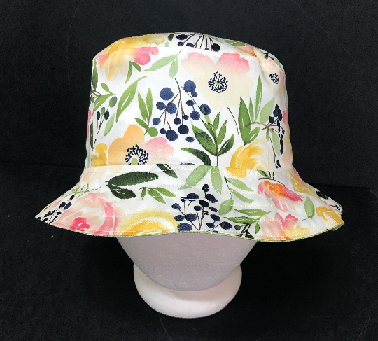 Front view, watercolor floral print bucket hat in yellows, peach and pink with green leaves on white background