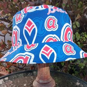 Atlanta Braves bucket hat with large throwback logos on blue background, front view of hat displayed on stand