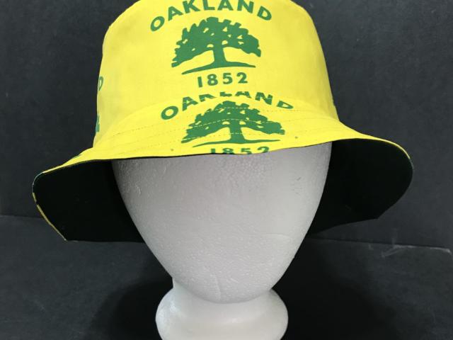 Front view of city of Oakland tree flag bucket hat on mannequin head