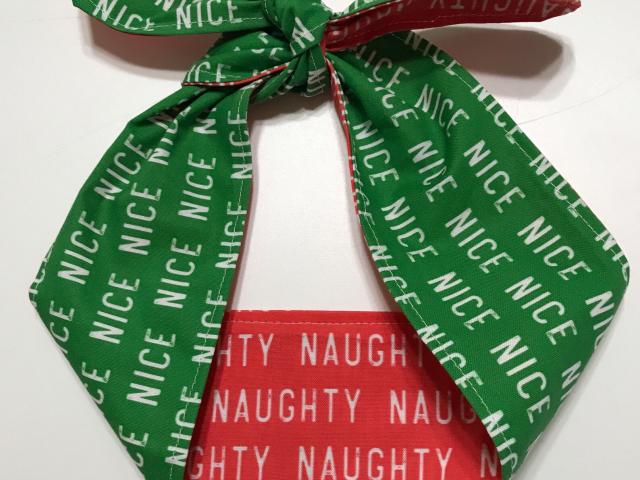 Christmas theme headband showing it tied on top, green Nice and red Naughty sides showing