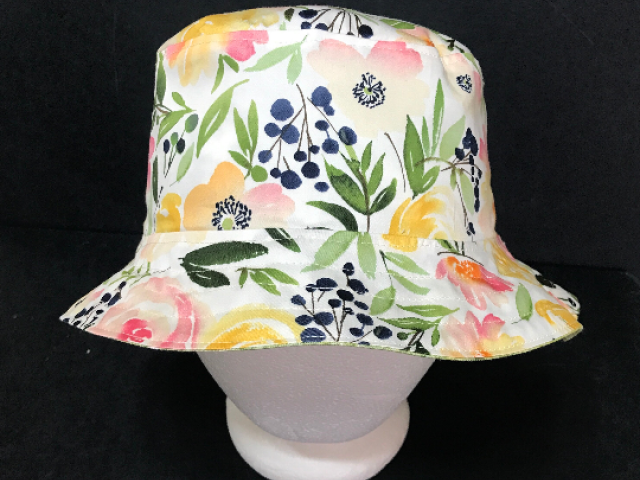 Front view, watercolor floral print bucket hat in yellows, peach and pink with green leaves on white background